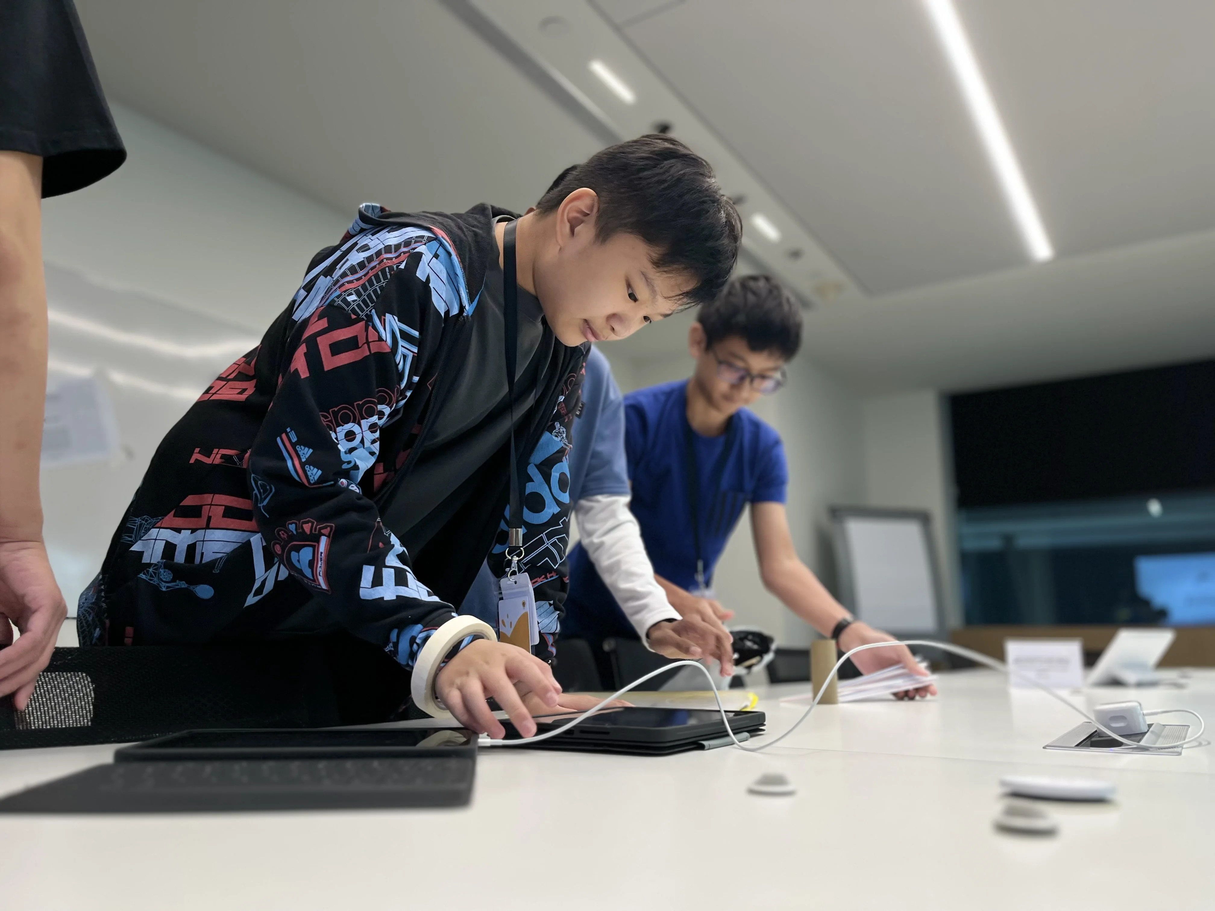 Ethan focused on a device during a collaborative technology workshop